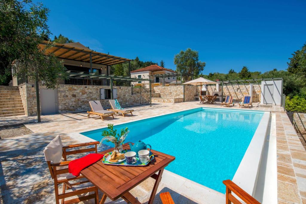 a villa with a swimming pool with a table and chairs at Villa Gionis in (( Romanátika ))