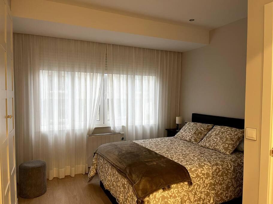 a bedroom with a bed and a window with curtains at Piso en el centro de Ferrol recién reformado. in Ferrol
