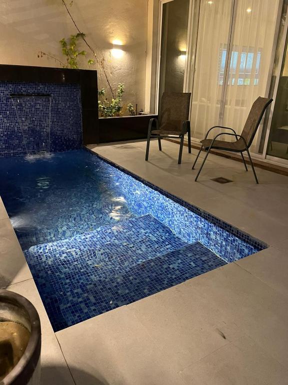 einen Pool in einem Wohnzimmer mit 2 Stühlen in der Unterkunft بيت عطلات مفروش بالخبر in Khobar