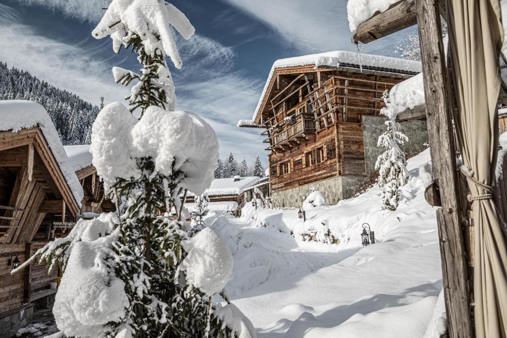 a tree covered in snow next to a building at Pool Luxury Lodge in Wagrain