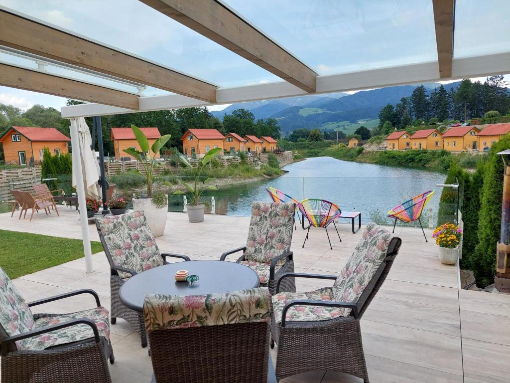 patio ze stołem, krzesłami i rzeką w obiekcie FERIENHAUS MOHN AM SEE w Spielbergu