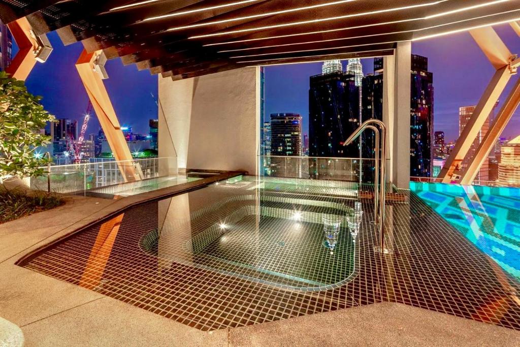 a balcony with a hot tub and a view of a city at Scarletz Suites KLCC by M Suites in Kuala Lumpur
