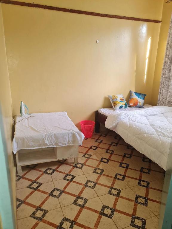 1 dormitorio con 2 camas y suelo de baldosa en Dala kwe, en Siaya