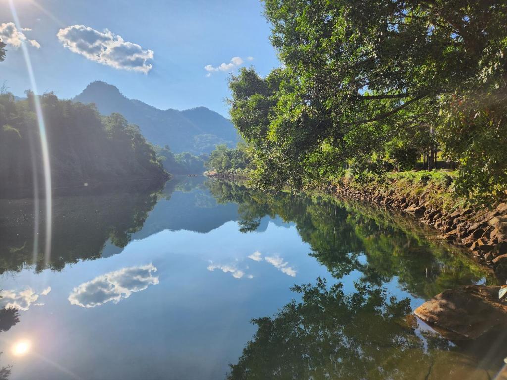 a river with a reflection of clouds in the water at Puprai Tarnnarm Resort in Thong Pha Phum