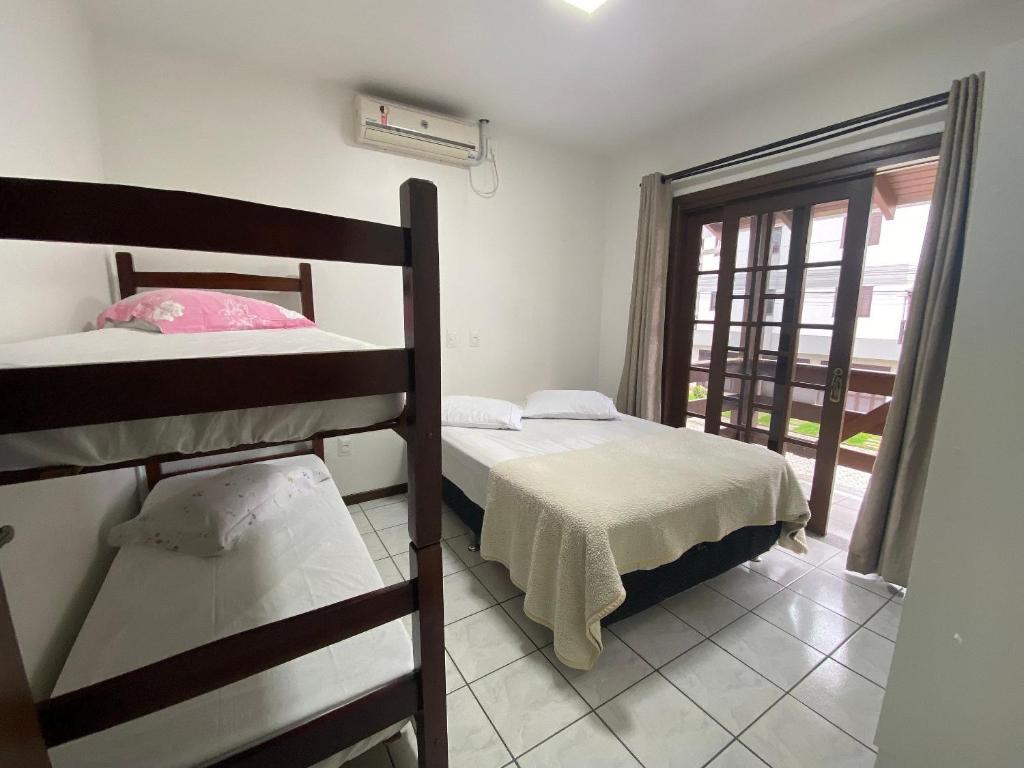 sypialnia z 2 łóżkami piętrowymi i oknem w obiekcie Casa em Bombinhas Próximo a Praia w mieście Bombinhas