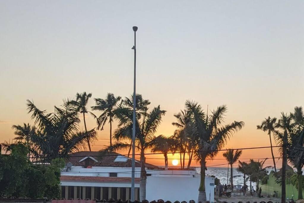 a building with palm trees in front of a sunset at Dpto. a unos pasos de la playa en Las Brisas in Manzanillo