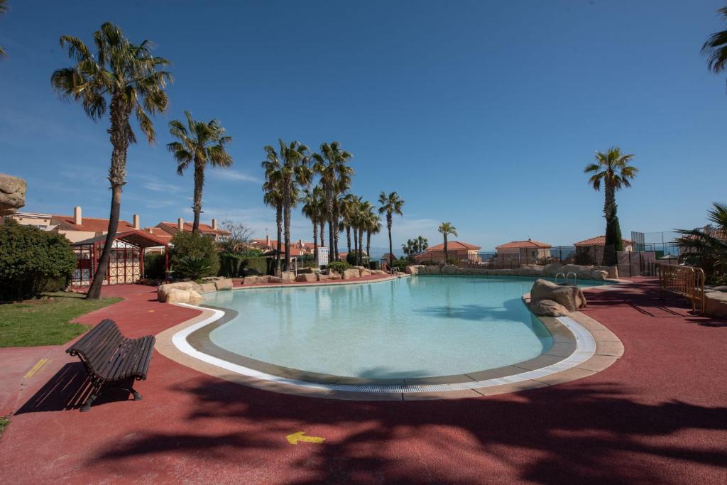 una piscina con palmeras en un complejo en Holiday Beach El Olivo, en Gran Alacant