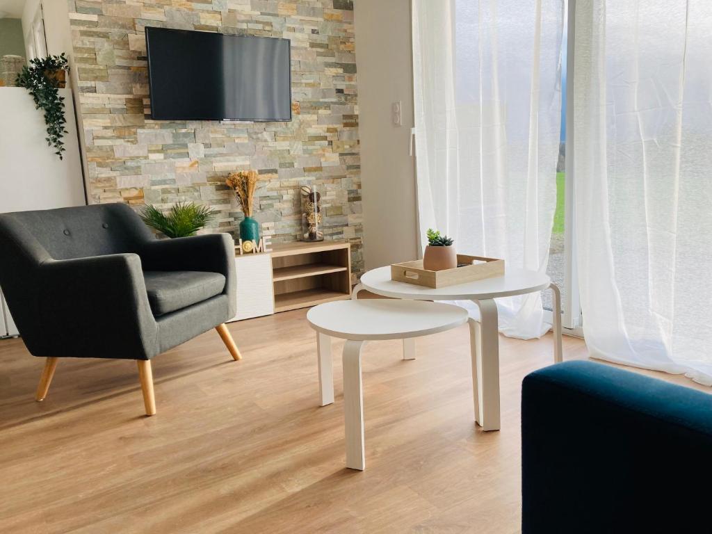 ein Wohnzimmer mit einem Stuhl, einem Tisch und einem TV in der Unterkunft Le gîte de Mireloup in Plerguer