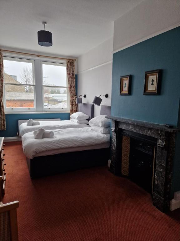 een slaapkamer met 2 bedden en een open haard bij Railway Hotel in Faversham
