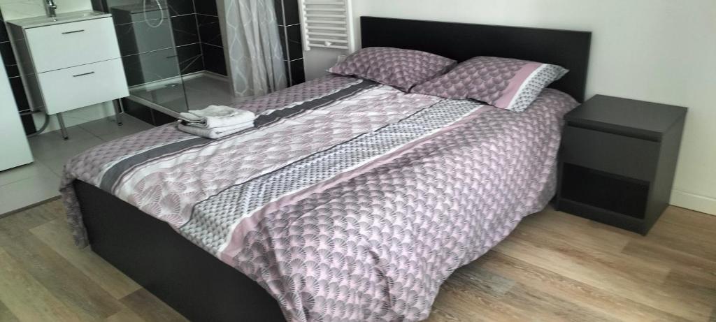 ein Schlafzimmer mit einem großen Bett mit lila Bettdecken und Kissen in der Unterkunft Appartement 2 pièces in Rive-de-Gier
