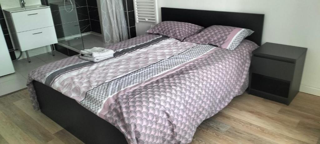 a bedroom with a large bed with purple comforter and pillows at Appartement 2 pièces in Rive-de-Gier