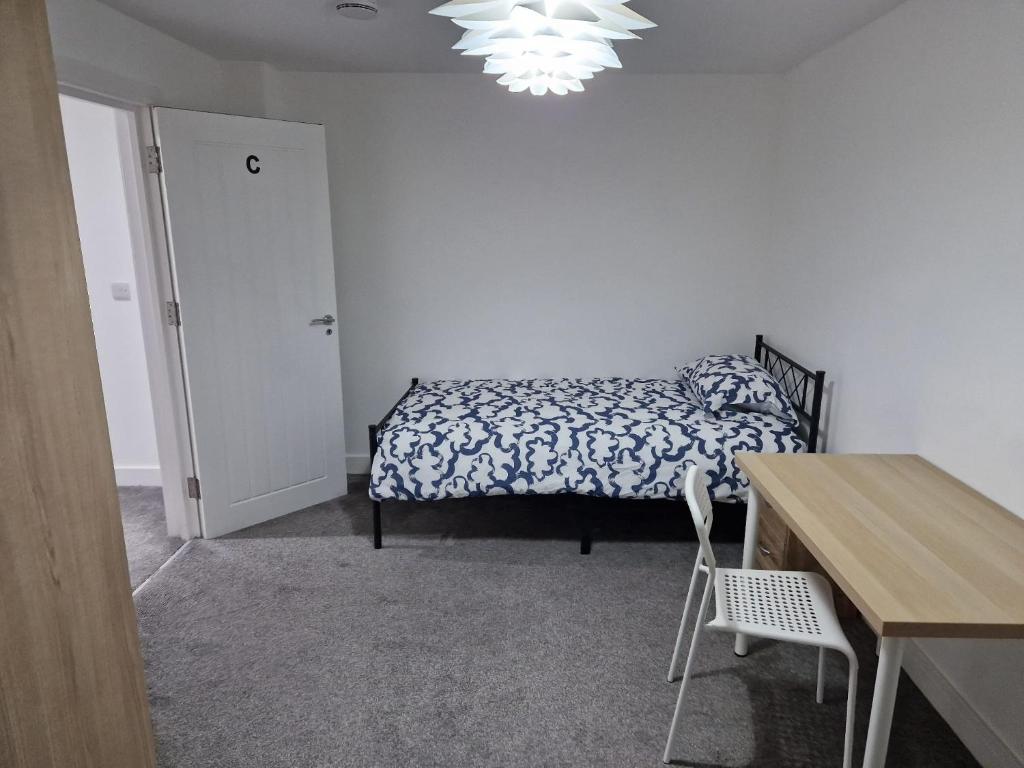a bedroom with a bed and a table and a desk at Spacious single bedrooms in central location with parking in New Barnet