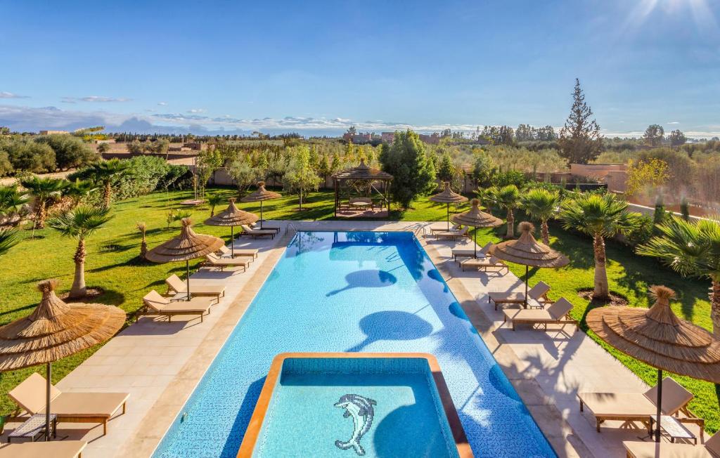 an image of a resort pool with chairs and umbrellas at leila farmhouse in Marrakech