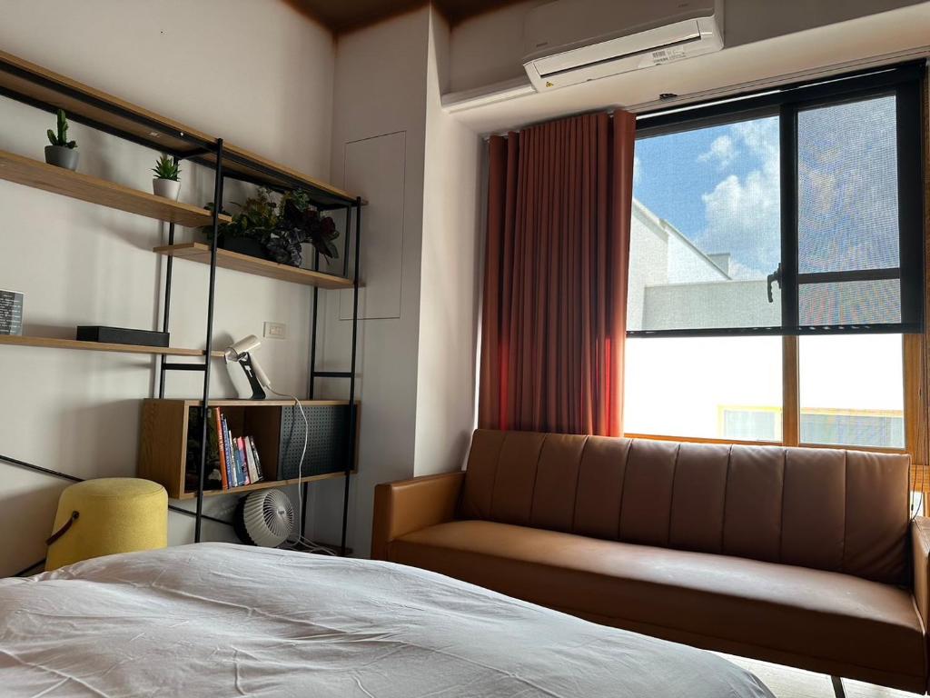 a bedroom with a bed and a window with a couch at 上水民宿 in Chiayi City