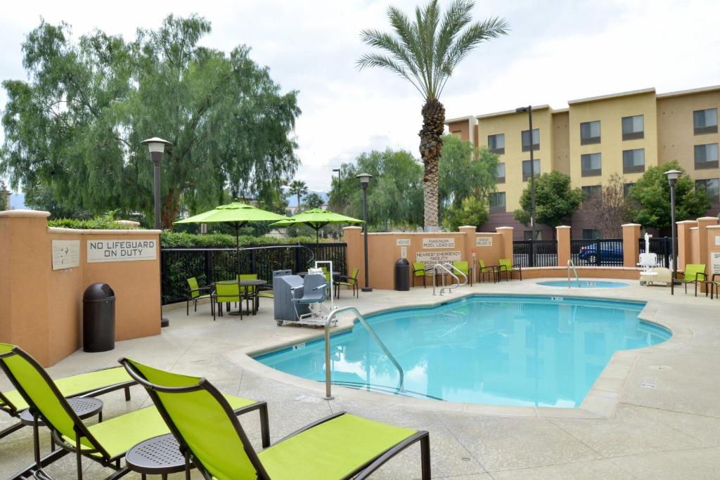 una piscina en un hotel con sillas y mesas en SpringHill Suites by Marriott Corona Riverside, en Corona