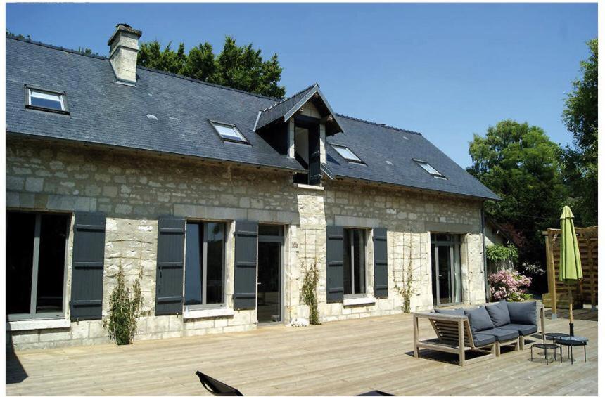 a stone house with a patio in front of it at Maison Vue Panoramique in Saint-Pierre-Aigle