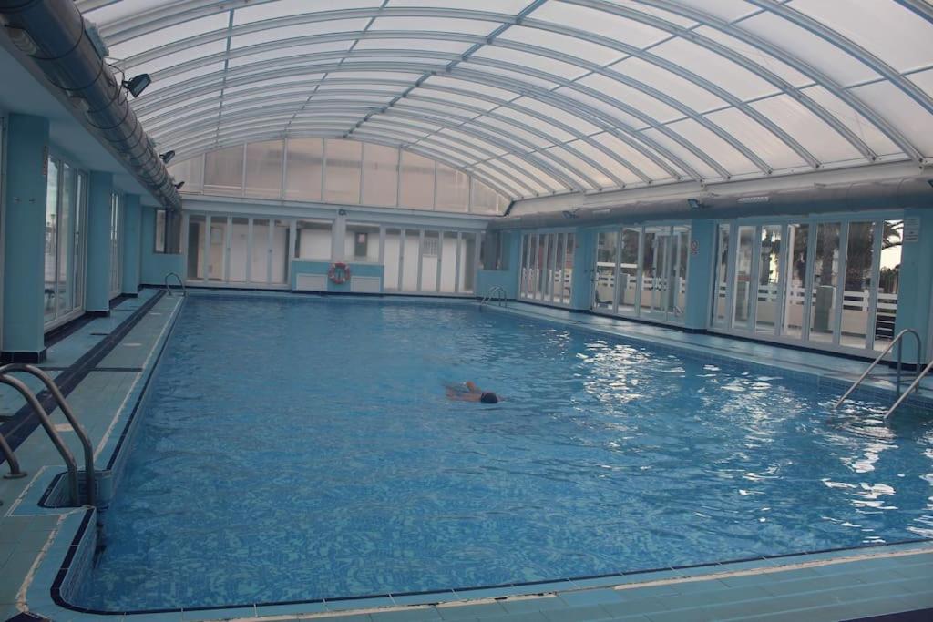 a person swimming in a swimming pool with a ceiling at Apartamento de lujo mar y montaña para todo el año con calefacción spa gimnasio y piscina climatizada in Tavernes de Valldigna