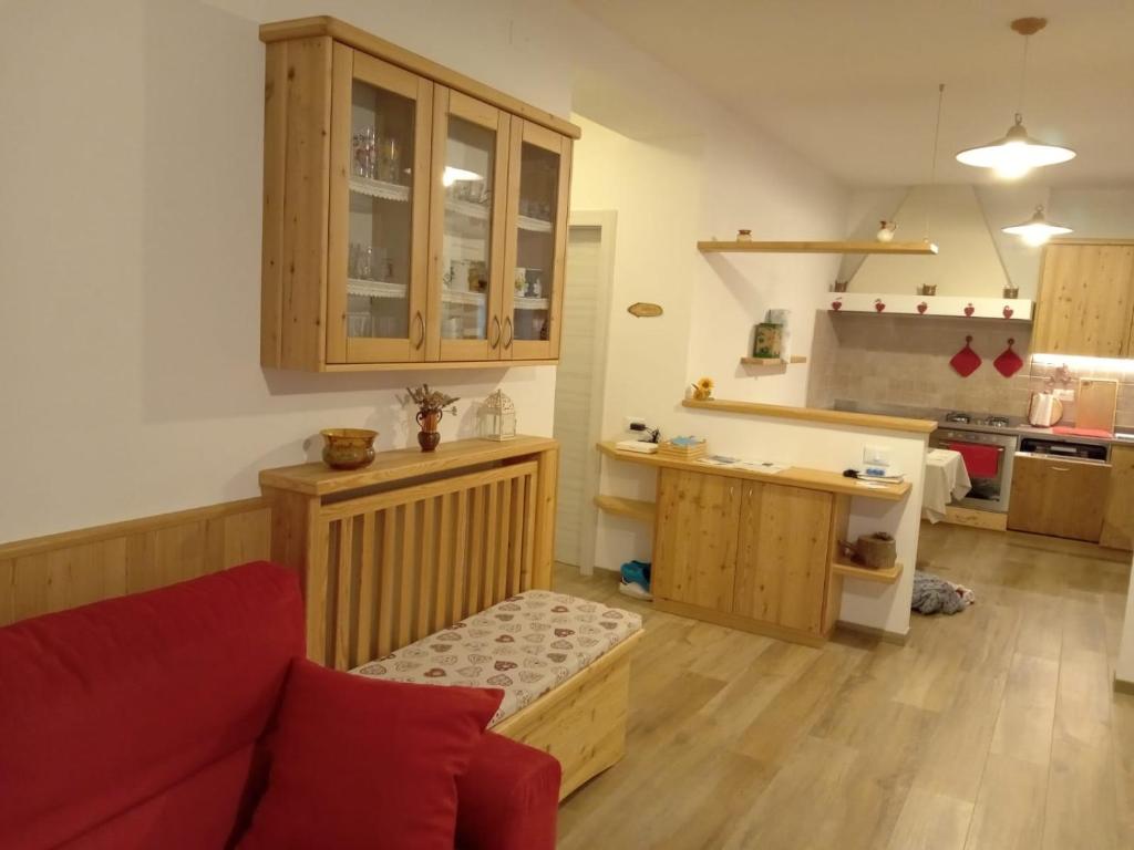 ein Wohnzimmer mit einem roten Sofa und einer Küche in der Unterkunft Casa vacanze Insieme in Baselga di Pinè