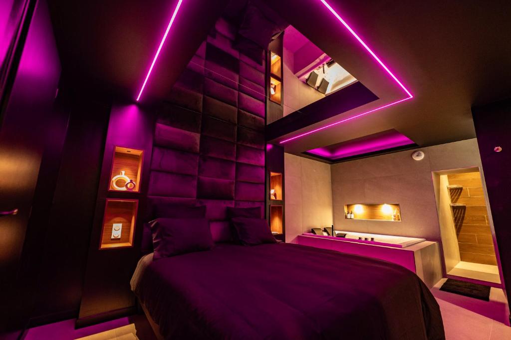 1 dormitorio con iluminación púrpura, 1 cama y bañera en LV Suites Jaude, en Clermont-Ferrand