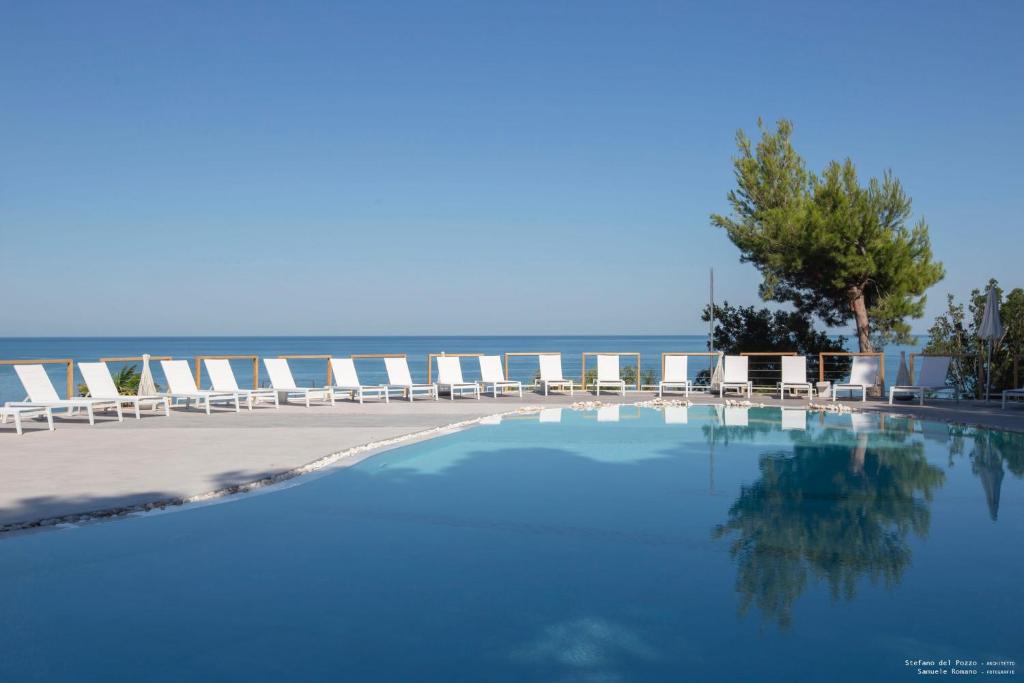 - une piscine avec des chaises et l'océan en arrière-plan dans l'établissement HOTIDAY Hotel Gargano, à Pugnochiuso