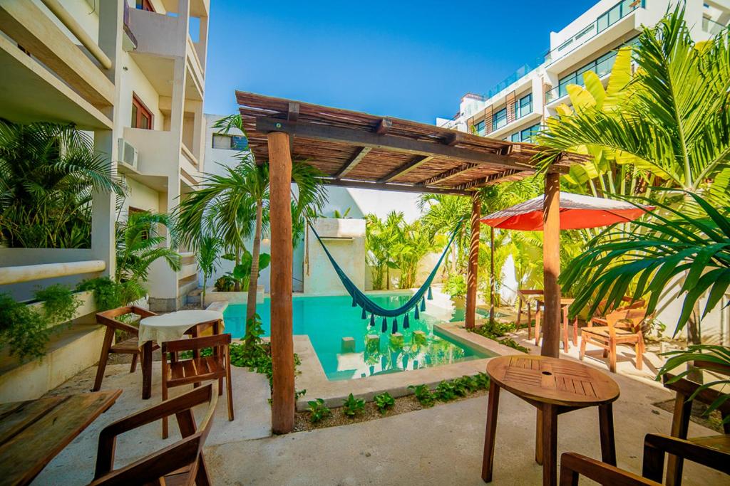 un patio con una hamaca, sillas y una piscina en Hotel San Vicente, en Playa del Carmen
