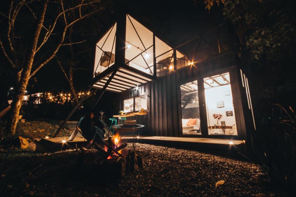 uma pessoa sentada em torno de uma lareira em frente a uma casa à noite em ZIRUMA HOUSE em Santa Elena