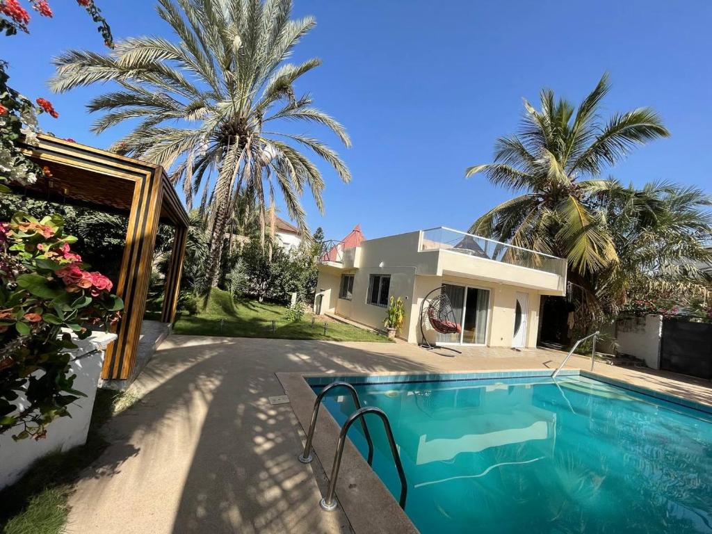 a house with a swimming pool and a palm tree at ParadisPlage, 1 minute de la mer in Saly Portudal