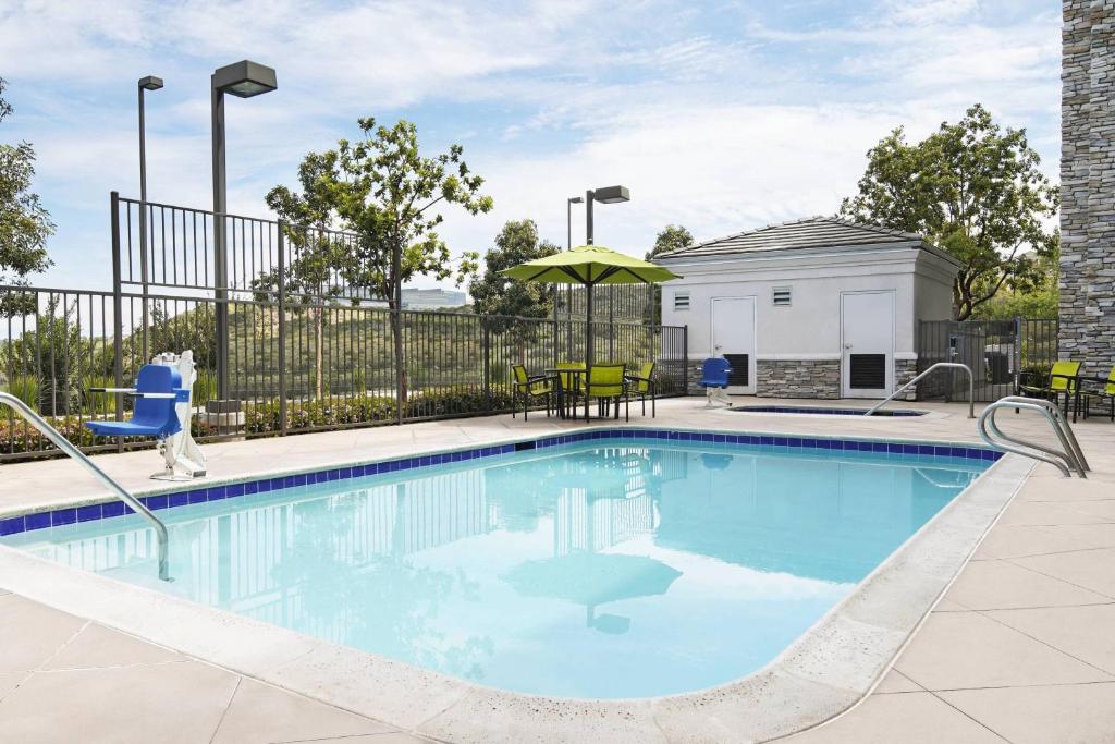 a swimming pool with chairs and an umbrella at SpringHill Suites San Diego Rancho Bernardo/Scripps Poway in Poway
