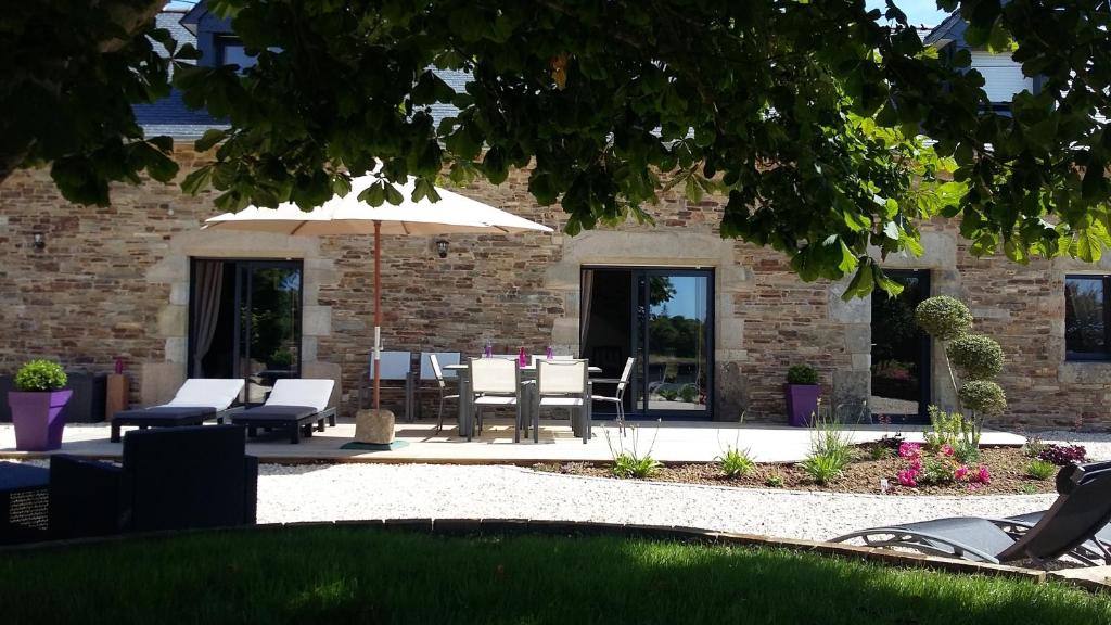 a patio with tables and chairs and an umbrella at Gîte de Kermal in Bannalec