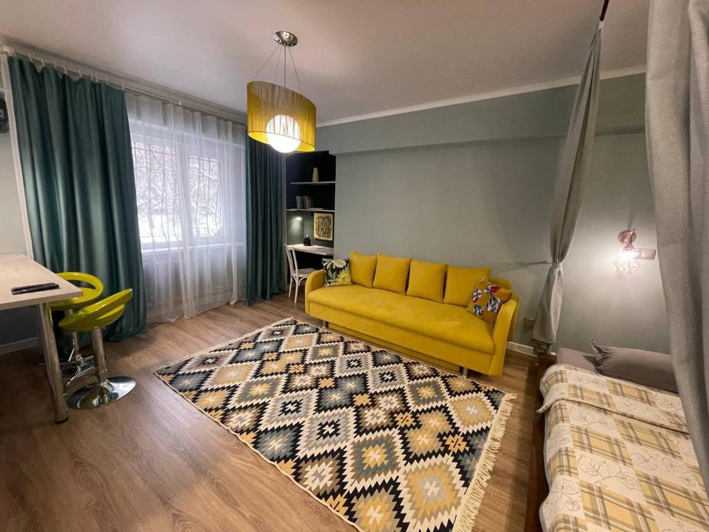 NicePlace in the old Center Almaty في ألماتي: غرفة معيشة مع أريكة صفراء وسجادة