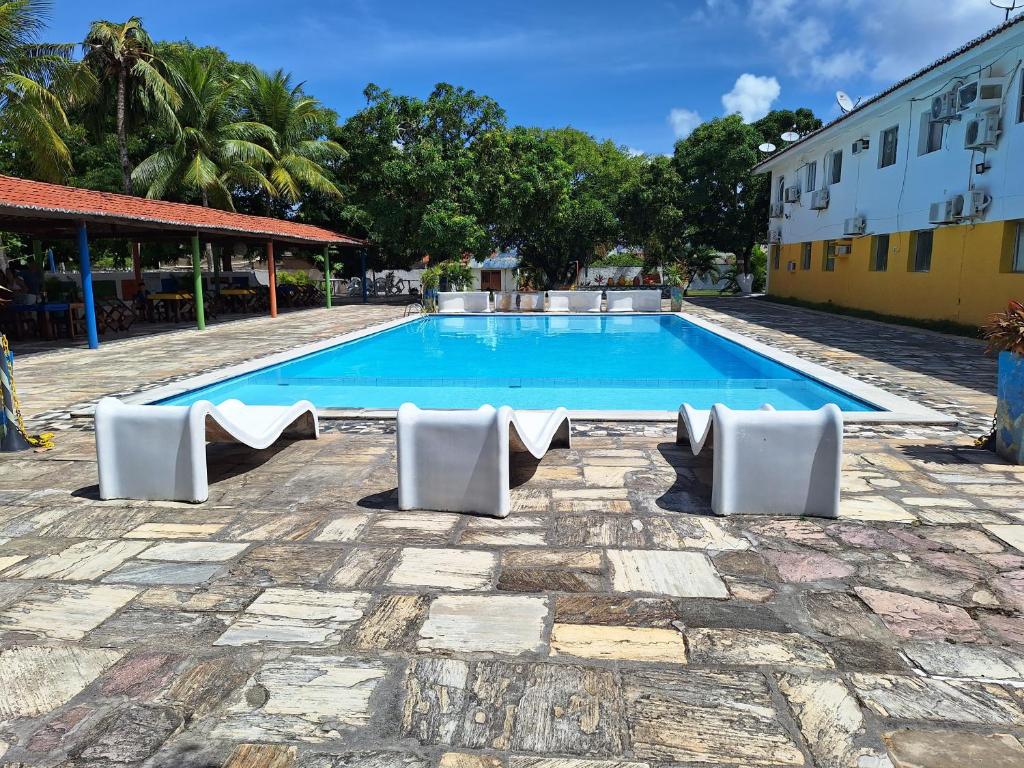 ein Pool mit weißen Stühlen und ein Gebäude in der Unterkunft Praia Flat in São José da Coroa Grande