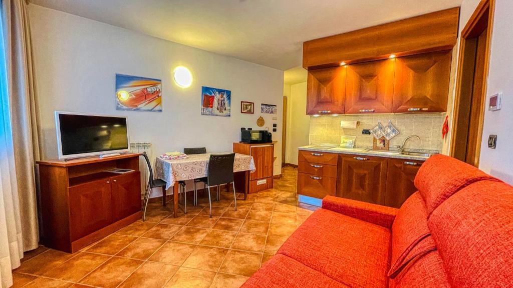 sala de estar con sofá rojo y cocina en Appartamento Smith Roero - Affitti Brevi Italia en Bardonecchia