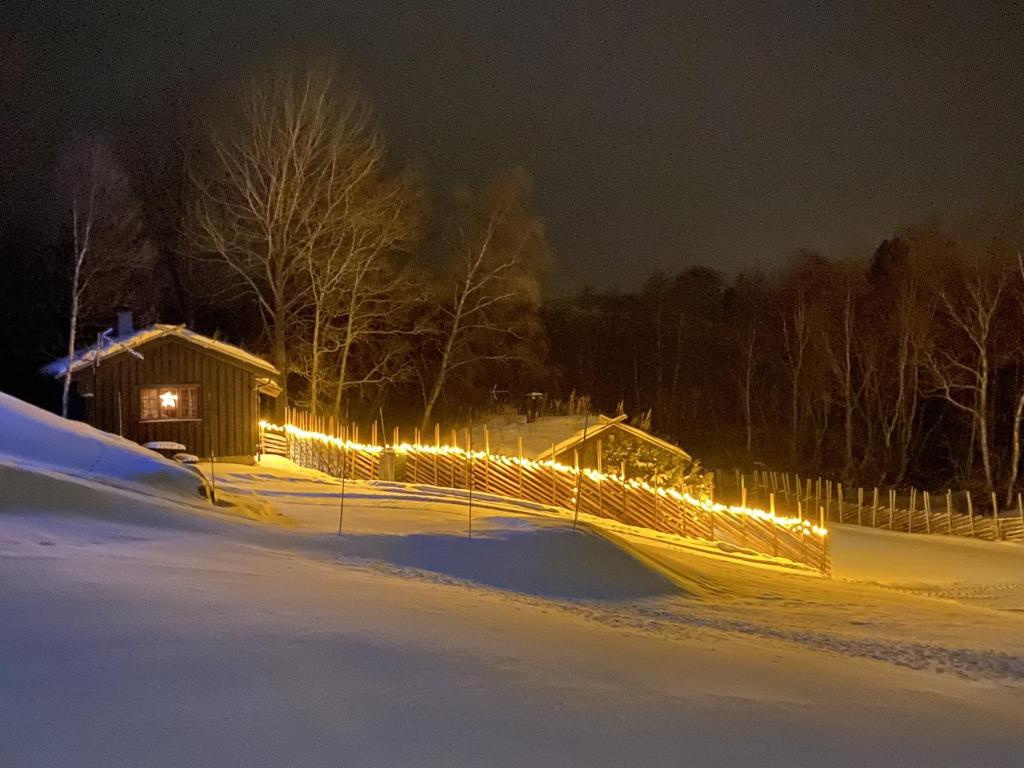 a fence with lights in a snowy yard at night at Rauland Hytteutleige in Rauland