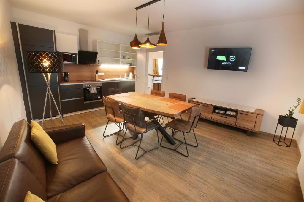 Zentrum Appartements Mörbisch في موربيش آم سي: غرفة معيشة ومطبخ مع طاولة وأريكة