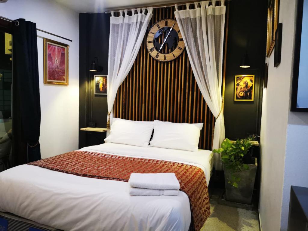 a bedroom with a bed with a clock on the wall at Max's Beach House in Pattaya South