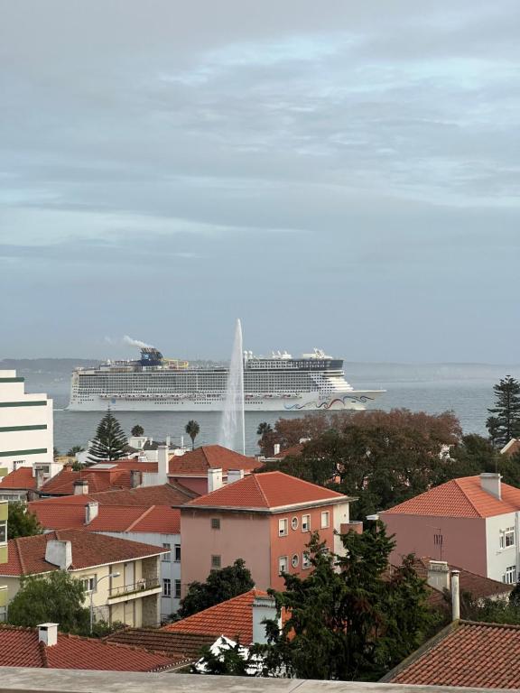 un grand bateau de croisière dans l'eau avec une ville dans l'établissement Top Sea View Lisboa - Oeiras, à Paço de Arcos