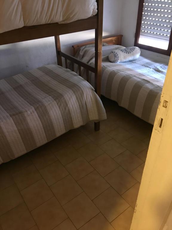 2 łóżka piętrowe w pokoju z podłogą wyłożoną kafelkami w obiekcie La 22 w mieście Balneario Claromecó