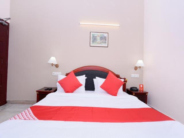 a bedroom with a red and white bed with red pillows at karthika residency in Cochin