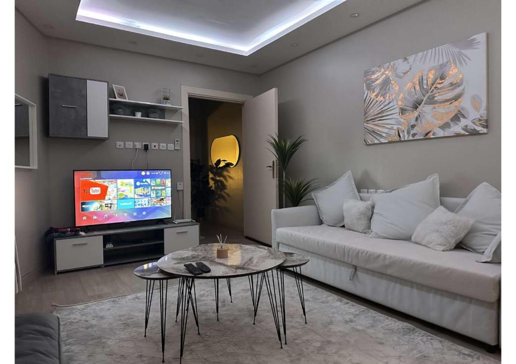 ein Wohnzimmer mit einem Sofa, einem Tisch und einem TV in der Unterkunft شقة تتكون من صالة وغرفة ومطبخ, حي النرجس in Riad