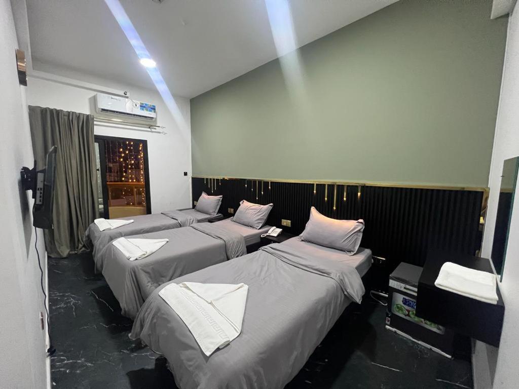 um quarto com 4 camas e almofadas brancas em GUEST INN HOTEL no Dubai
