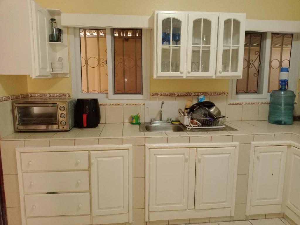 La cuisine est équipée de placards blancs, d'un évier et d'un four micro-ondes. dans l'établissement Hermosa casa de Huéspedes, à Tegucigalpa