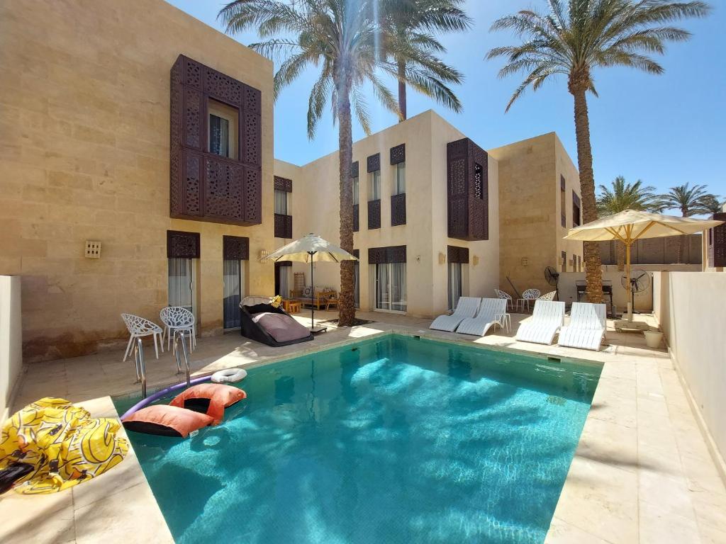 a swimming pool in front of a house with palm trees at Nayah Boutique Stays in Hurghada