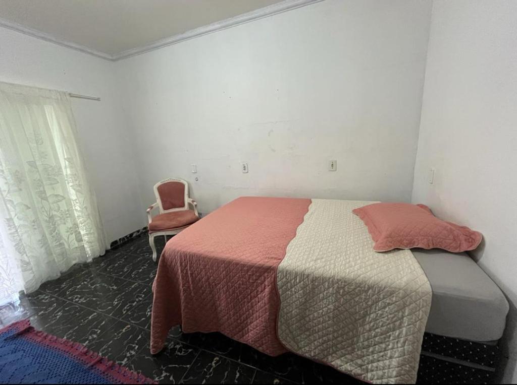 a bedroom with a bed and a chair at Pensão da Rose in Sorriso