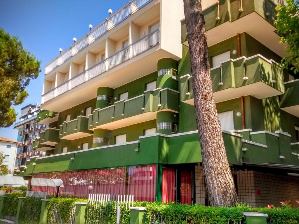 an apartment building with green balconies and a tree at Hotel Etna in Riccione