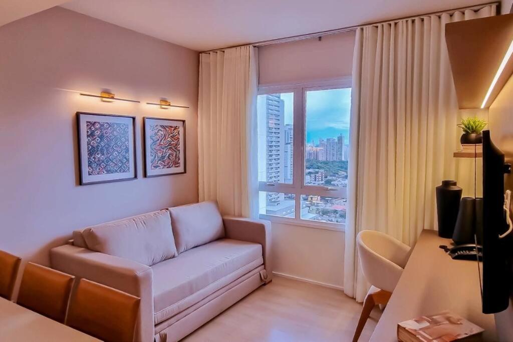 a living room with a couch and a large window at Blend Smart Marista 2 Quartos in Goiânia