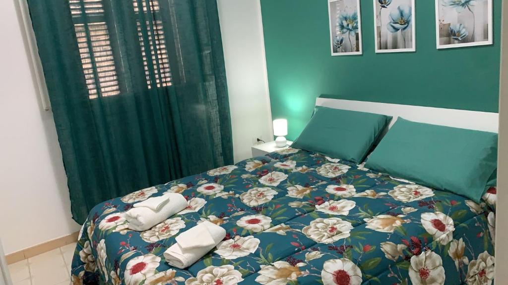 1 cama con edredón azul y almohadas en The Apartments Nordino, en Mazara del Vallo