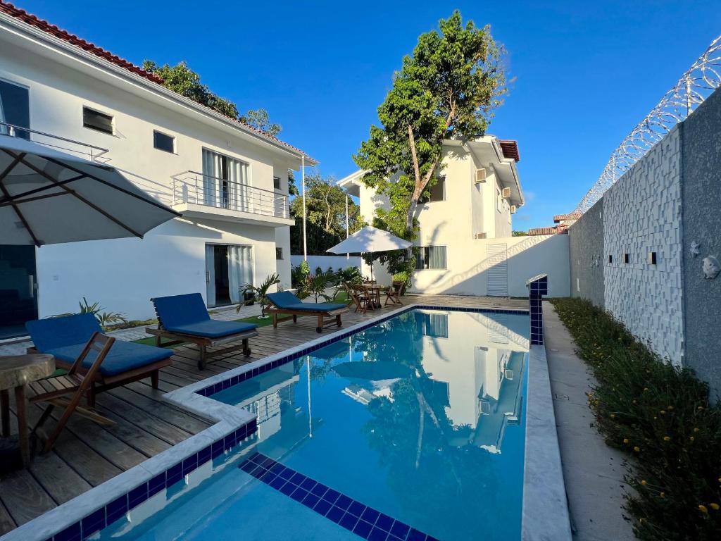 uma piscina com mesa e cadeiras ao lado de um edifício em Casa céu de estrelas em Arraial d'Ajuda