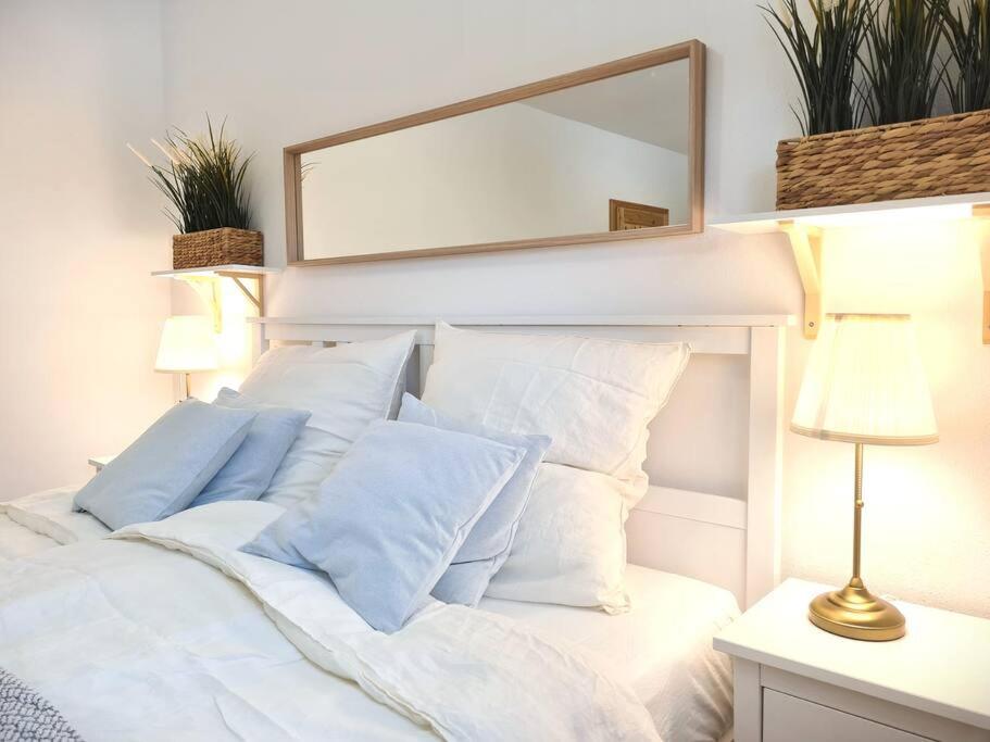 a white bed with white pillows and a mirror at Familientraum auf 120 m2 in Rostock in Rostock