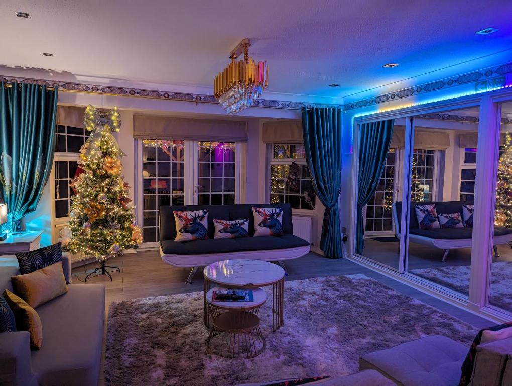 a living room with a christmas tree and a couch at FINN VILLAGE "Raspberry Cottage" Private Garden, 6-seater Hot Tub, Firepit & Pizza Stove in Glasgow