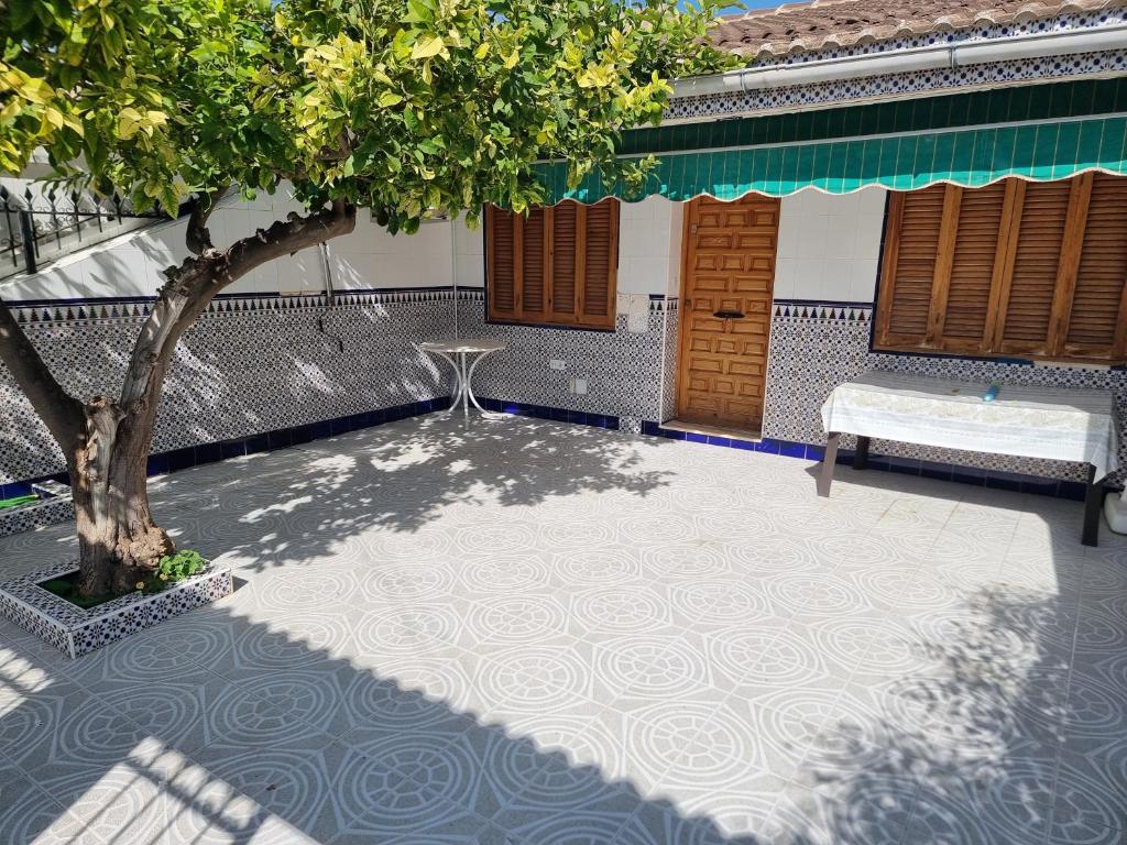 un patio con una mesa y un árbol frente a un edificio en Casa Tranquila cerca del Mar en Santiago de la Ribera